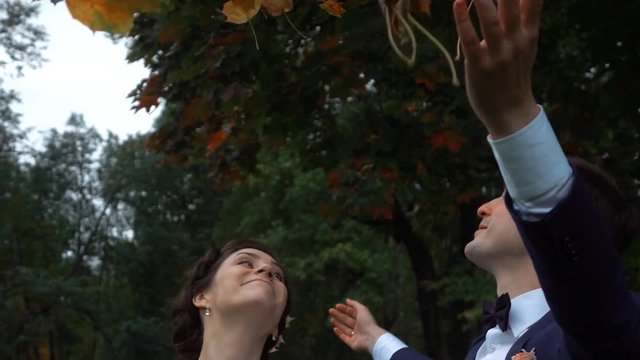 Wedding couple in autumn park. Thet throw up green orange and red leaves in air. Smile, laughing and happy of marriage. Extreme high-speed camera slow motion shot