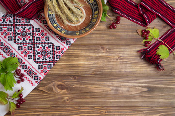 wooden background with Ukraine ethnic elements  - embroidery, viburnum,spikelets of wheat, bowl, dishes