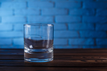 Empty whiskey glass on brick wall background. Alcohol drinks, bar concept