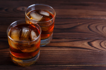 Whiskey with ice cubes on wooden table, copy space.  Alcohol drinks, bar concept