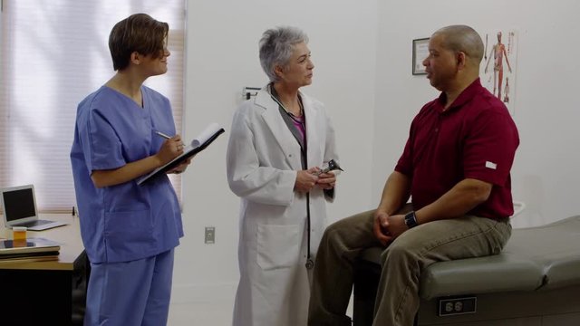 Doctor and nurse speaking to male patient in medical office