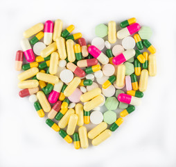 Colorful drug pills in shape of heart on white background, pharmaceutical concept