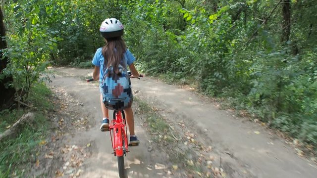 Child with a bicycle in nature. A little girl in a helmet is riding a bicycle.