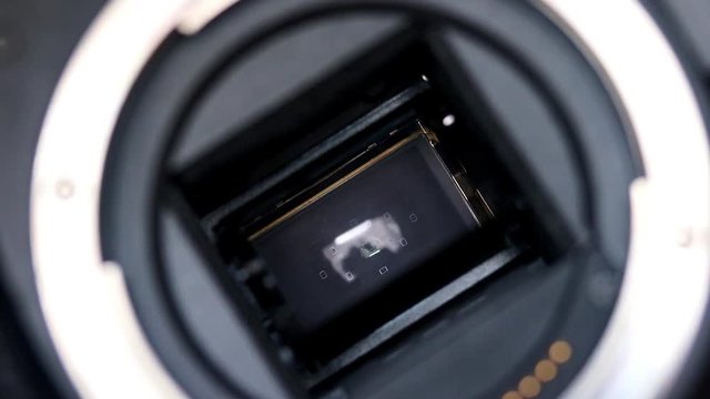 Open digital Camera APS-C shows mechanism of shooting, closeup. Shooting digital camera with sound of shutter, close-up view. Mirror and shutter mechanism DSLR camera. Camera Shutter Close up.