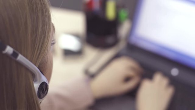 The operator of the hotline with headsets, sit at the computer in the office and advise clients. Workers call-center, a woman talking to customers. She prints on the computer and answers questions.