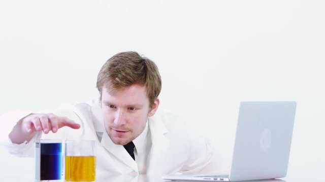 Scientist using laptop and studying liquids
