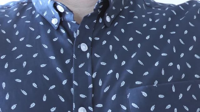 Close-up. The man button up his shirt.
