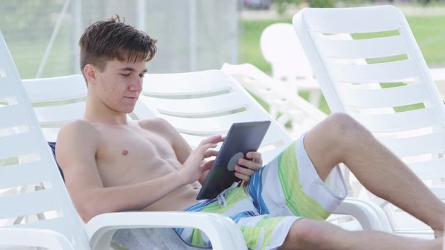 Young boy using tablet by the pool