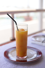 Glass of refreshing cool mango lassi sweet Indian drink over restaurant table light background
