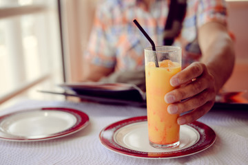 Glass of refreshing cool mango lassi sweet Indian drink over restaurant table light background