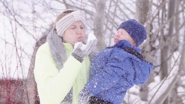 Slow motion mom playing with snow with her son