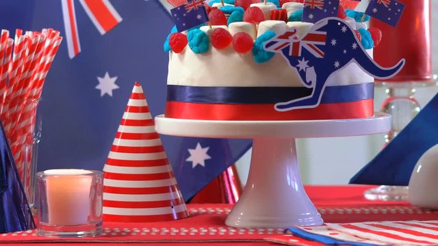 Australian celebration party table with showstopper cake decorated with candy, stars and flags, panning across and up.