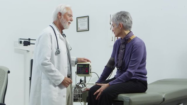 Eldery doctor checking heart rate of elderly patient