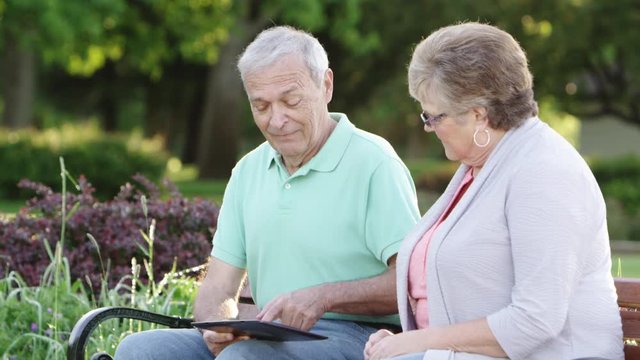 Elderly couple using tablet in park