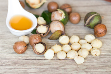 Closeup view of natural macadamia oil and Macadamia nuts on wooden board. Healthy food