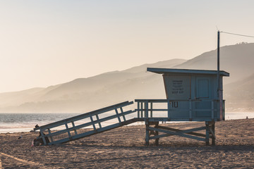 A lifeguard station with a foggy background and mountains on Zuma Beach in Malibu, California.  