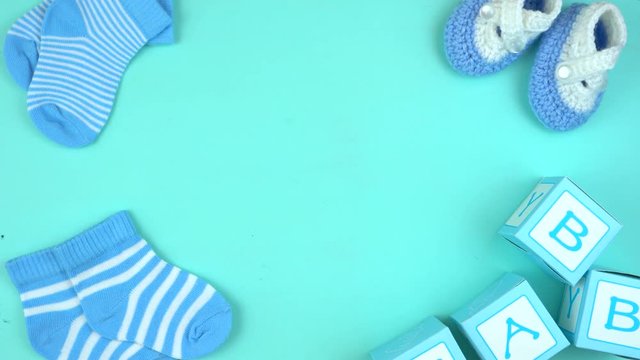 4k Baby boy nursery clothing and accessories overhead on blue wood table, layout with copy space, time lapse.