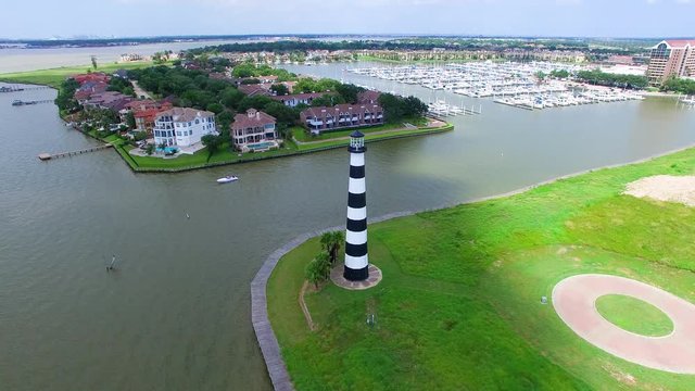 Black and White lighthouse on a lake next to a boat marina takin from a drone