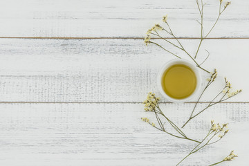 Yellow limonium caspia flowers with a cup of tea on white wood background with copy space