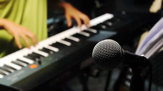 Music band concept background.Selective focus microphone and blurred man playing electric piano.Mix variety object on the modern home recording.An idea musician play the instruments at the studio.