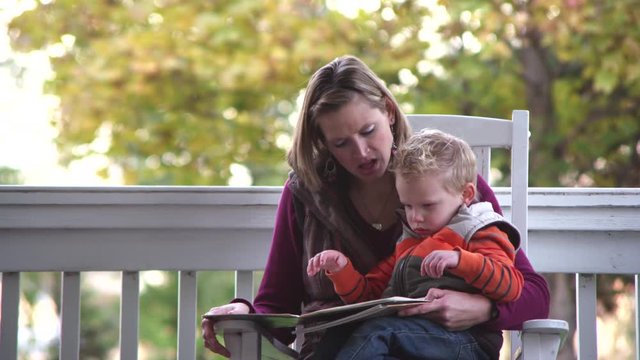 Mother reading a book to son in autumn