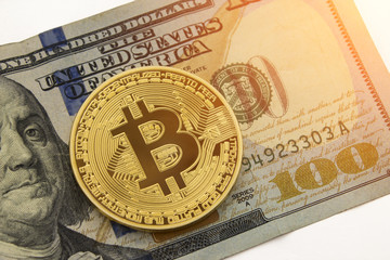 Bitcoin over the United States dollar with white background and copyspace room for text and wording.  Golden physical bitcoin crypto currency.