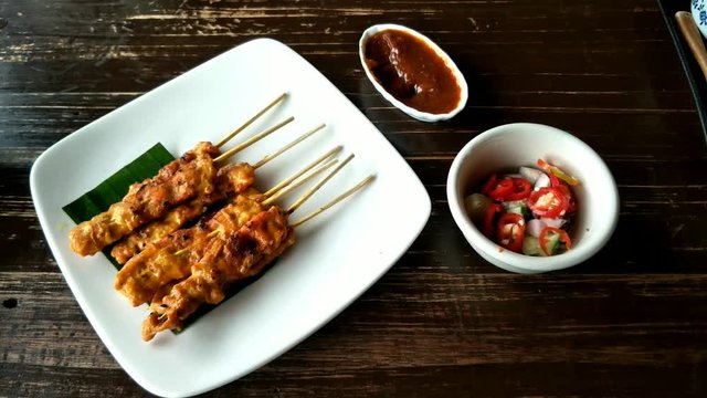 Thai food, grilled pork Satay with peanut sauce and pickles from cucumber slices and onions in vinegar