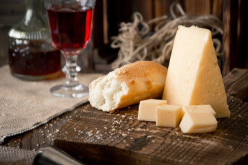 Cheese and bread on the wooden board and red wine. Rustic style