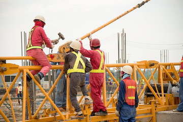 Workers in the process of removing a tower crane disassembling it bit by bit. The motor for...