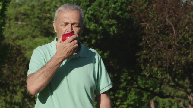 Portrait of elderly man eating an apple