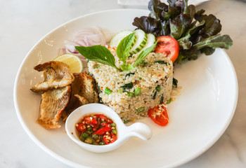 decorative fried rice with crispy fish on white plate in modern restaurant