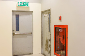 Building Emergency Exit with Exit Sign and Fire Extinguisher in a modern building.