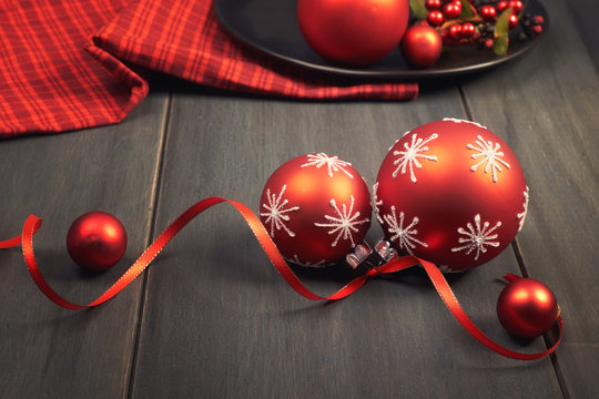 Red Christmas Baubles Tied With Ribbon And Red Napkin On Wood