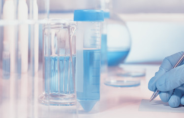 Scientific or medical background with gloved hand holdong microscopic slide glass