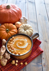 Spicy pumpkin soup with ginger, onion and garlic in a dark ceramic pan