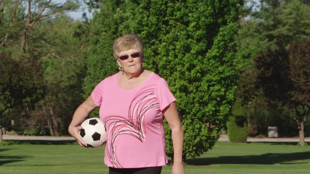 Elderly woman holding a soccer ball in the park