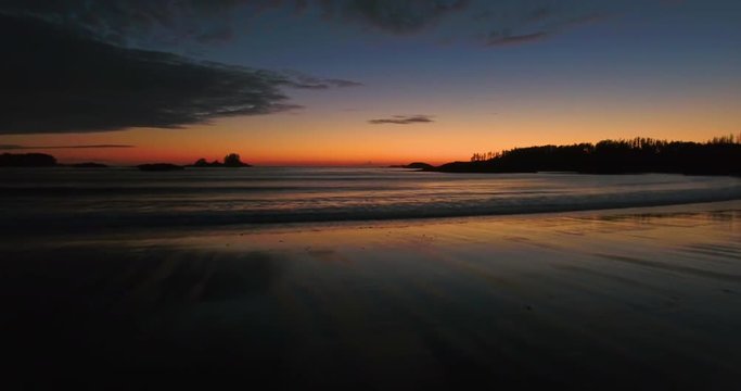 Slow aerial shot flying over a beach during an orage sunset