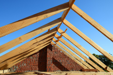 Wooden roof construction. Unfinished House building. Installation of wooden beams at construction the roof truss system of the house.