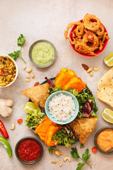 Spicy vegetable and meat  Indian snacks with jeera rice, various salads and sauces on rustic surface. Top view, blank space