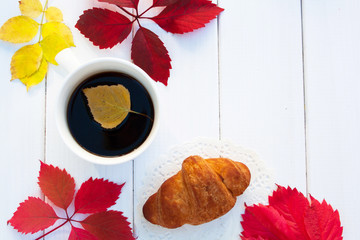Fototapeta na wymiar cup of coffee and red autumn leaves of grapes on a white wooden background