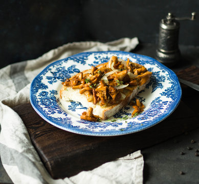 Big toast with fried chanterelles on an old blue plate on a dark background. season food