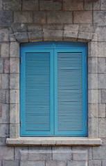 Fototapeta premium Blue wooden shutters on rustic stone wall.