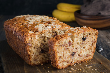 Homemade banana bread loaf with walnuts sliced on wooden cutting board. Closeup view, horizontal