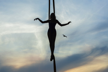 Woman balancing actor on the background of the setting sun, contours of the figure.