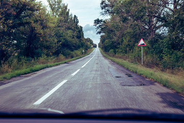 Dark asphalt road in the forest. View from the car.