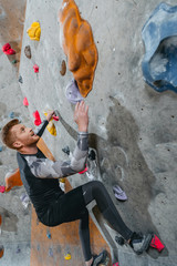 Obraz na płótnie Canvas Man climbing wall with grips