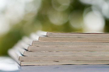 Time to read concept. Pile of stacked magazines on the blur background. Closeup, selective focus