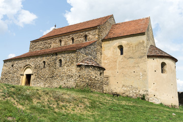 Obraz premium Cisnadioara, Transylvania, Romania. Fortified medieval church on top of rock hill in Cisnadioara near Sibiu, Transylvania, Romania. Cloudy summer day.