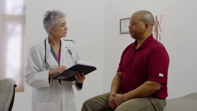 Doctor taking notes and talking to patient