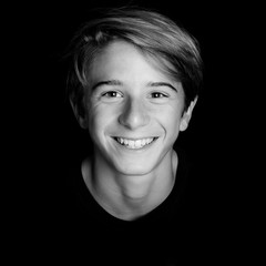 young blonde smiling guy portrait on black background - black and white photo